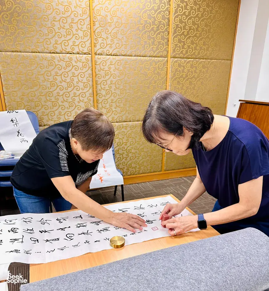 Learners practise Chinese brush calligraphy at a table in a Singapore studio, writing a blessing at calligraphy workshops in Singapore