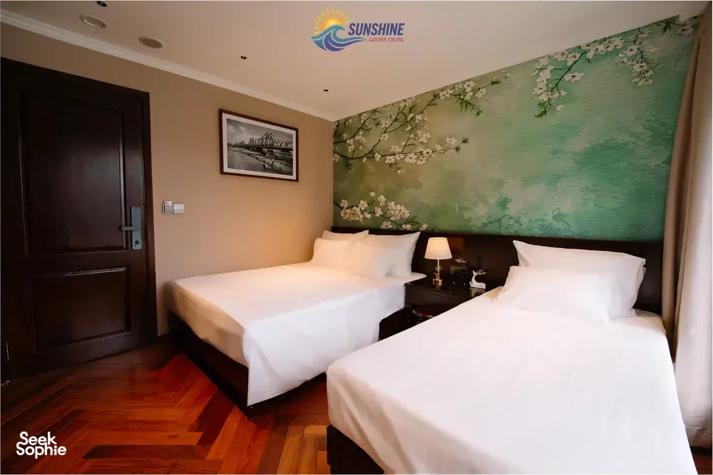 Sunshine Golden Cruises cabin bedroom on a Cat Ba cruise with two beds, warm lighting and a mural-style wall behind