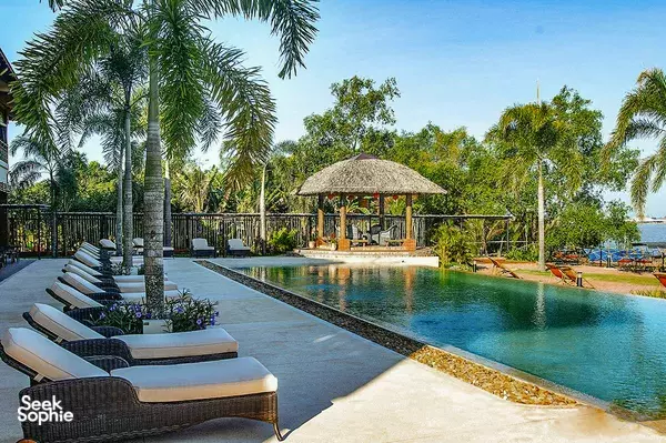 Tropical resort pool with sun loungers and a thatched gazebo at The Island Lodge in Mỹ Tho, Mekong Delta