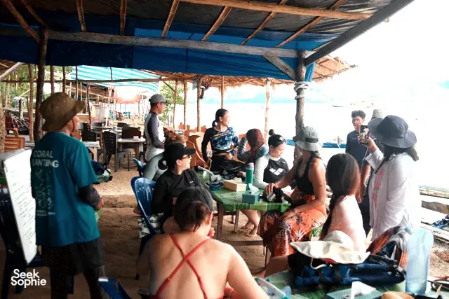 People gathered under a shelter preparing coral planting supplies with Rinca Coral Nursery Program before restoring reefs in Labuan Bajo