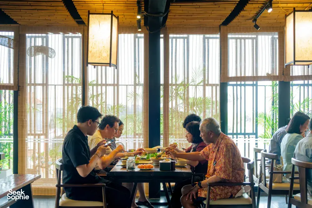 Group seated at a dining table with Vietnamese dishes in a bright Hanoi room during an Up Travel Vietnam rare agarwood tour