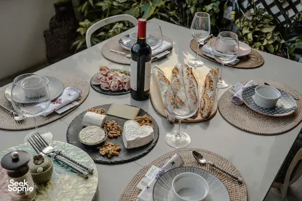 French baguette meal spread on a dining table in a cosy Singapore loft, with wine bottle and plates for sunset drinks