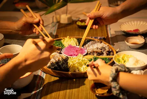 Primateve diners pass chopsticks while sharing grazing platters at a communal table during private dining Singapore