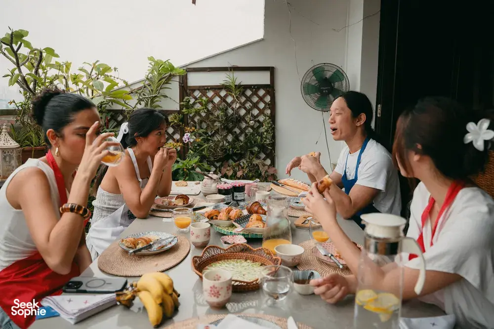 Croissant baking class in a Singapore home: guests around a shared table with drinks and pastries while the French chef guides