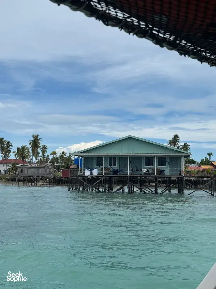 Banglo air berbung bumbung biru kehijauan dengan dek panjang di atas laut jernih Semporna, bersama Bigfin Divers