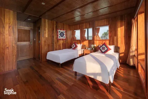 Cat Ba Ocean Cruises suite interior on a Cat Ba Boutique Cruise, showing two neatly made beds and bay views