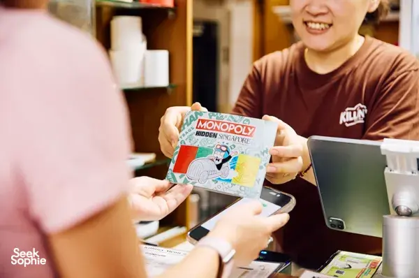 Monopoly Hidden Singapore cards in participants’ hands during a game briefing in Singapore, for exploring Singapore hidden gems