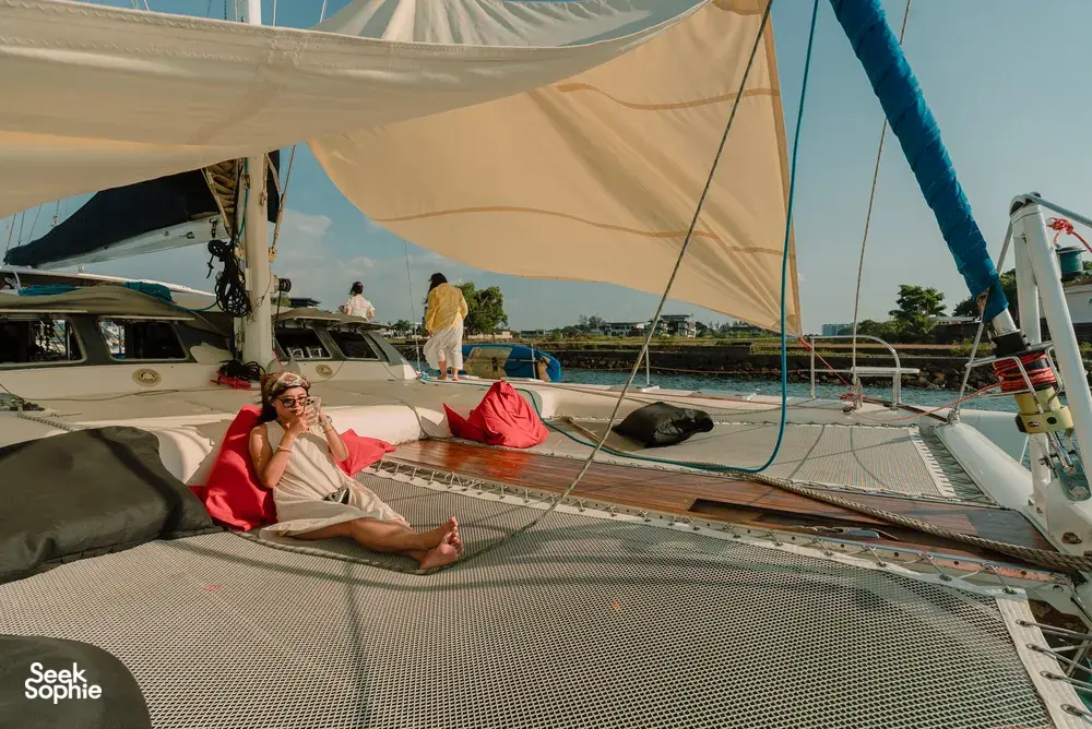 Travellers relaxing on the upper deck with sail canopies on a catamaran near Kota Kinabalu’s coastline as the cruise continues