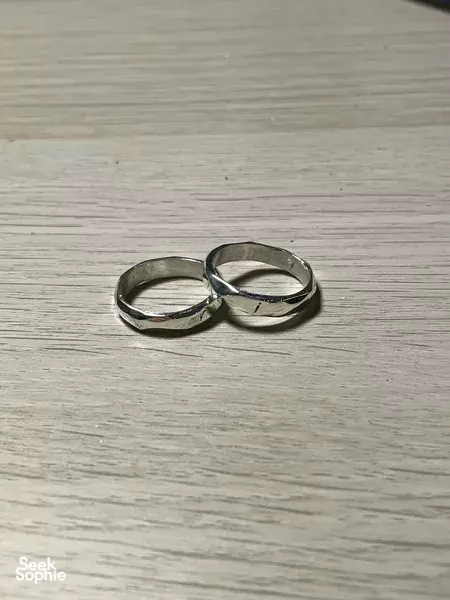 Two polished silver rings on a wooden work surface from a basic silversmithing workshop in Singapore for workshops in Singapore
