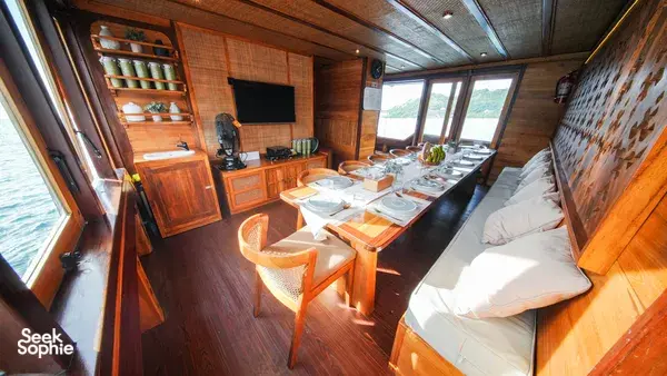 Dining table set on a wooden phinisi lounge for onboard meals during the 3D2N Komodo cruise in Labuan Bajo
