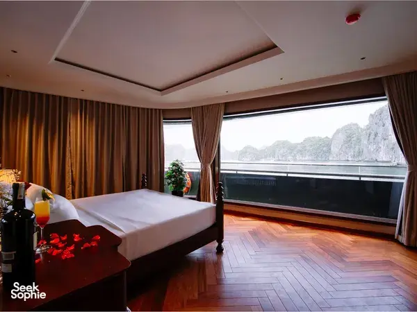 Bilik kabin pelayaran mewah Cat Ba oleh Sunshine Golden Cruises dengan katil king dan tingkap dari lantai ke siling menghadap tebing batu kapur