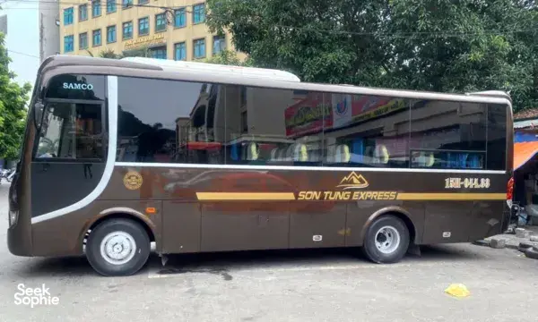 Son Tung Express coach bus parked on a street for the Cat Ba to Halong transfer, ferry tickets included