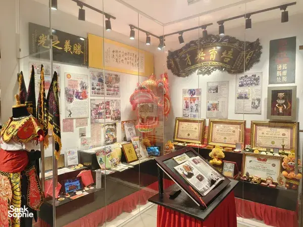Ho Chi Minh City Chinatown exhibition room with glass cases, lion-dance costumes, photos and certificates honouring martial arts heritage