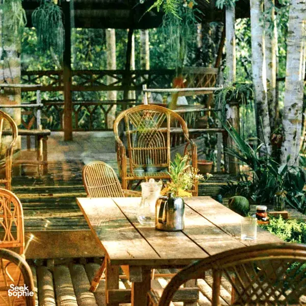 Rattan chairs around a wooden table with bottles and herbs on the veranda of Ngapuh Homestead, surrounded by bamboo, near Kuching