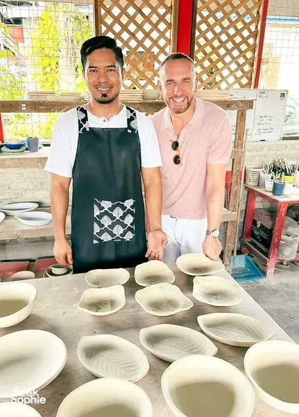 Two pottery makers at Ilham Ceramic Studio in Langkawi arrange white ceramic bowls on a workbench during a workshop