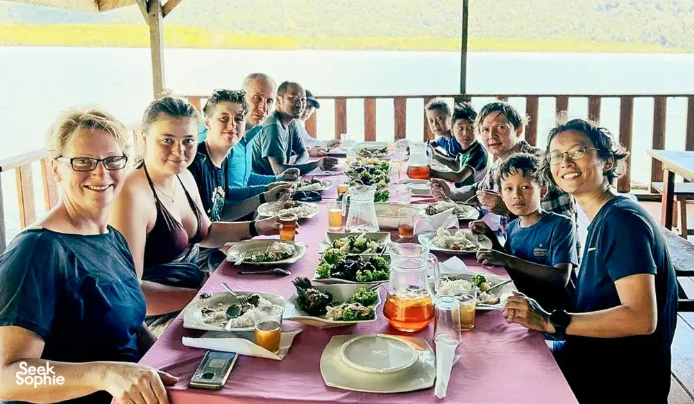 Meal shared by travellers at a long table on the deck during a Langkawi trip for mangroves, caves and island swimming