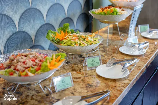 Halong Bay party cruise buffet table with salad bowls and serving utensils along a stone counter top, ready for guests to eat