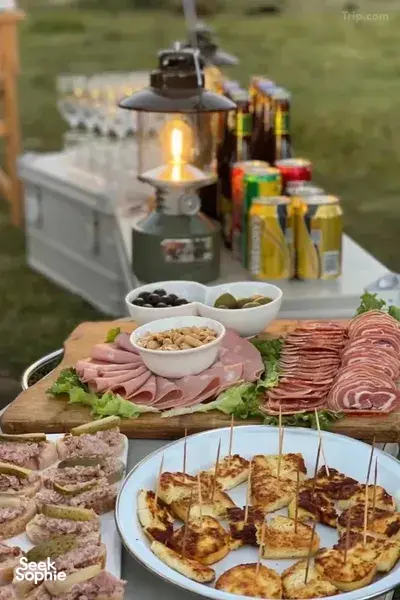 Outdoor caravan dining table with cured meats, olives and grilled bread squares, set up beside a camping stove in Shangri-La