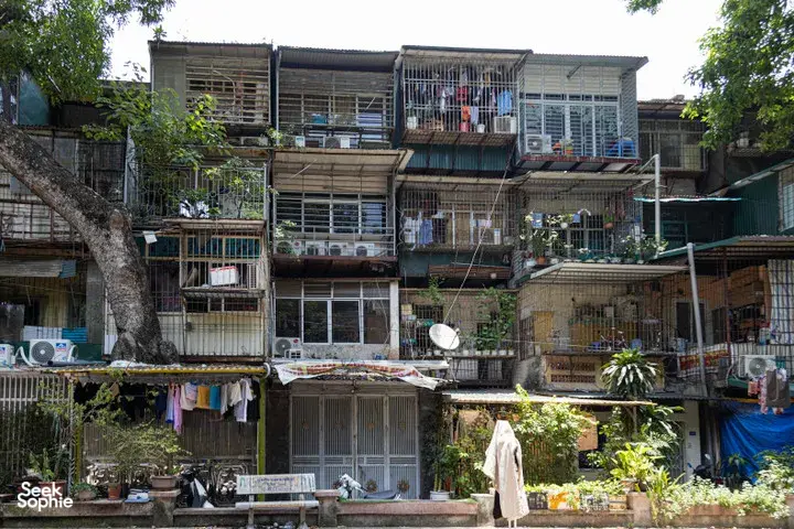 Weathered multi-storey apartment blocks with metal-framed balconies and laundry lines in a Hanoi collective housing neighbourhood