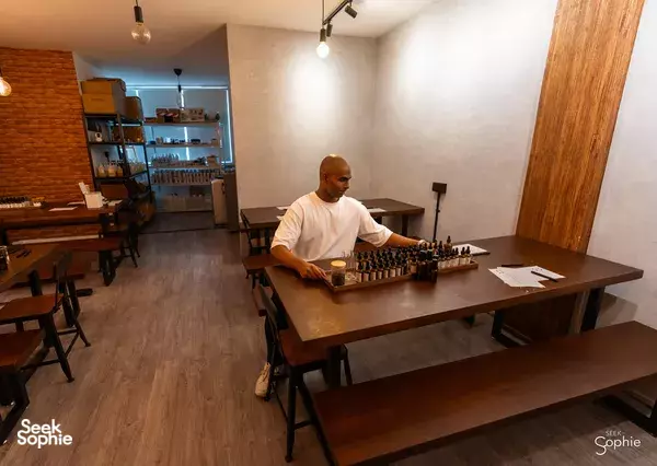 Bruce working at a table of essential oil bottles and mixing tools, preparing scent blends for workshops in Singapore