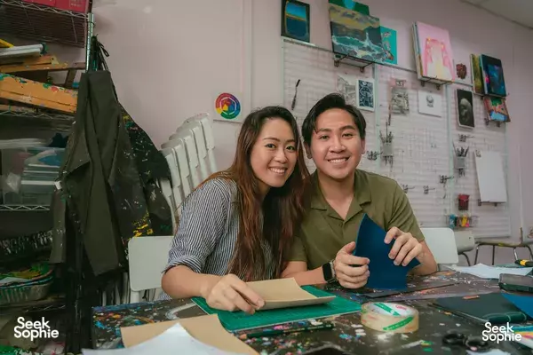 Two makers at Avant-Garde Art Space in Singapore arrange leather journal materials at a hands-on crafting session workshops in Singapore