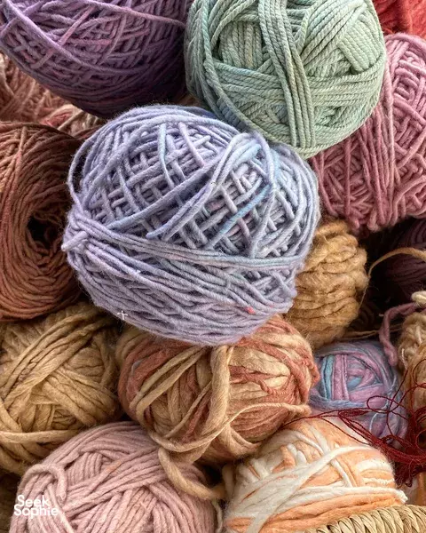 Close-up of rolled cotton yarn balls in pastel colours for Thai weaving, arranged on a textile bundle at Kalm Village, Chiang Mai