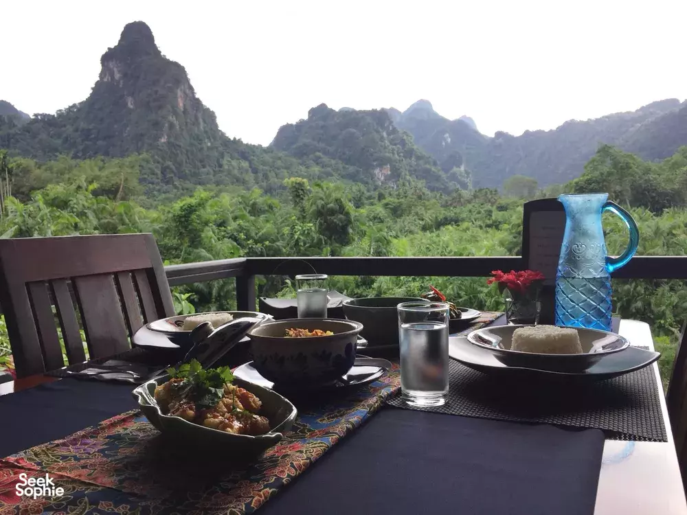Outdoor dining table with cups and dishes on a rainforest-view terrace during jungle dining in Khao Sok National Park
