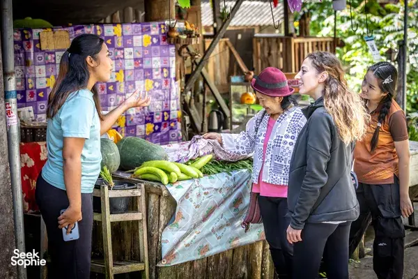 Participants sort fresh vegetables on an outdoor prep table during a Mae Kampong forage-to-table cooking class in Chiang Mai