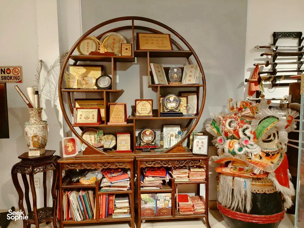 Lion dance costume head and wooden shelves of training manuals and memorabilia inside a kung fu museum in Ho Chi Minh City