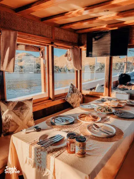 Set table with plates and condiments inside a Deluxe phinisi dining area, framed by sea views during a Komodo cruise, Komodo Island
