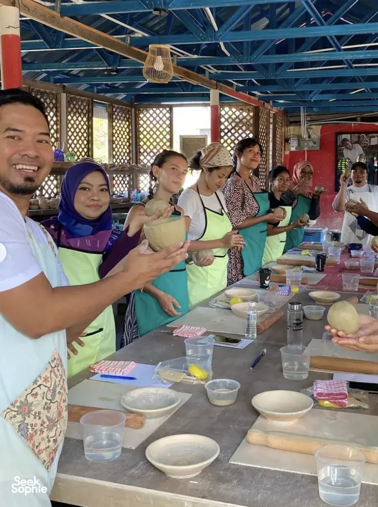 Group pottery class in a covered Langkawi studio, visitors shaping and decorating small bowls at shared worktables