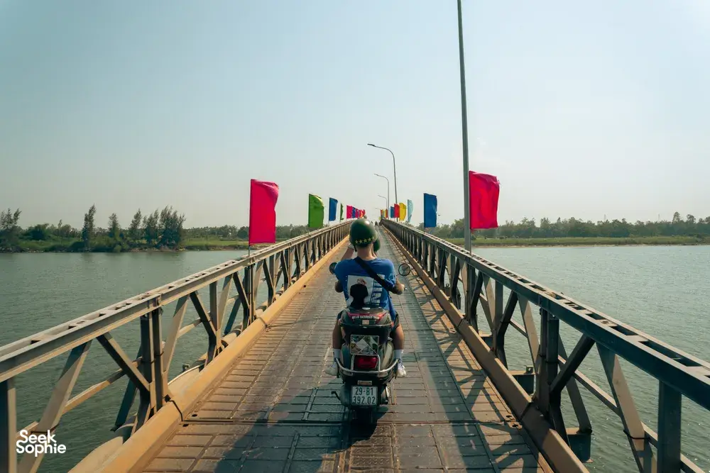 Naik Vespa melintasi jembatan panjang di atas sungai besar di Hoi An dalam rangkaian highlight bertema perahu keranjang bersama Hoi An Backroad Tours