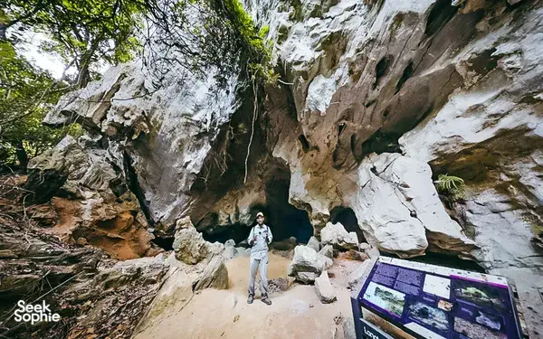 Solo traveller walking along a rocky cave passage in Langkawi, part of an eco discovery combining caves and mangroves