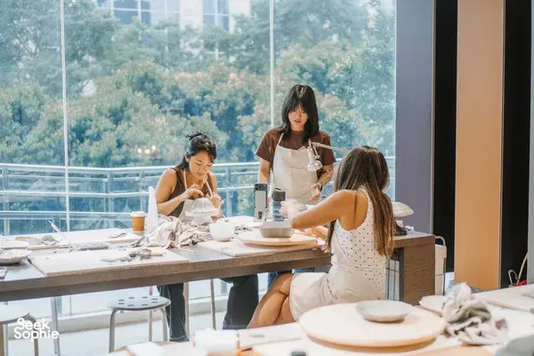 Pottery workshop in a Singapore ceramics studio, participants handcrafting antique European-style plates at worktables by large windows