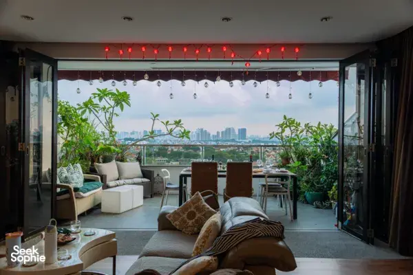 View into a cosy Singapore loft with string lights and city skyline through open doors, plants by the dining table