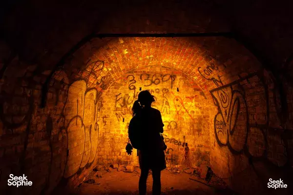 Backlit silhouette inside a graffiti-covered brick passage at Mount Faber during a hike to war ruins, Singapore