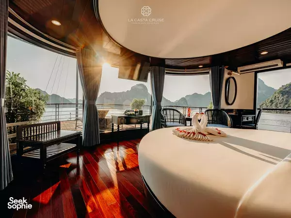 La Casta cruise suite cabin with a made-up bed, floor-to-ceiling windows and sunset sea views on this 3D2N trip in Lan Ha Bay