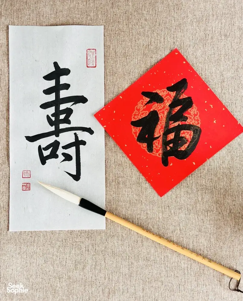 Calligraphy practice sheet with a bold black Chinese character and red seal, plus a brush on paper in Singapore—workshops in Singapore