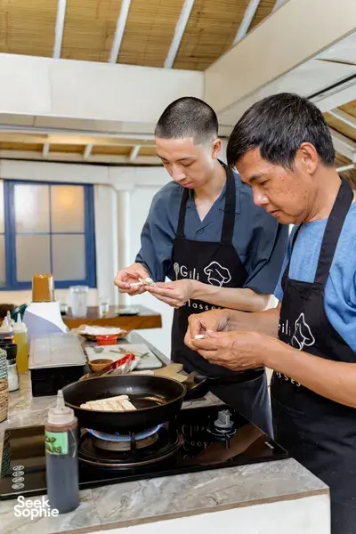 Host-led cooking class on Gili T, Lombok: participants pan-fry ingredients while learning to make peanut sauce