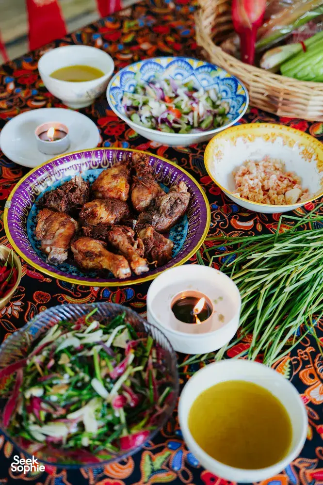Kota Kinabalu Indigenous Sabahan meal spread with grilled chicken, colourful salads, herbal stems and lit tea-candles