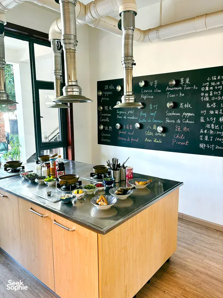 Lijiang cooking station for a Yunnan market-to-table class, with ingredient bowls and recipe notes on a chalkboard