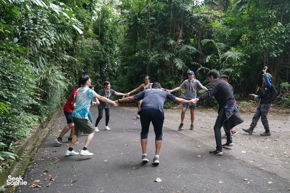 Team trekking along a paved path through tropical rainforest on a Fort Serapong discovery adventure in Singapore