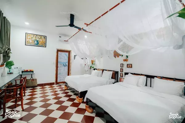 Cozy twin beds under a white canopy net in the Lovely Pottery Homestay bedroom in the Mekong Delta, South Vietnam