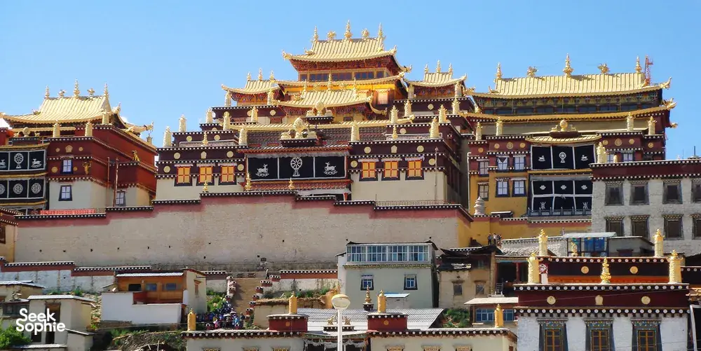 Gilded Tibetan monastery with ornate multi-roof façade in Shangri-La, backed by a clear blue sky in the Tibetan highlands