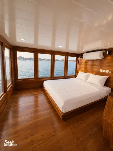 Wooden phinisi bedroom with large sea-view windows for a 3D2N shared Komodo cruise by La Famille in Labuan Bajo