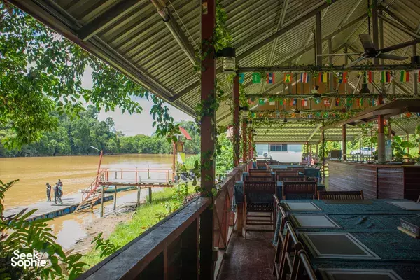 Open-air dining terrace at Sukau Greenview Lodge with long benches and hanging bunting, overlooking the riverside in daylight