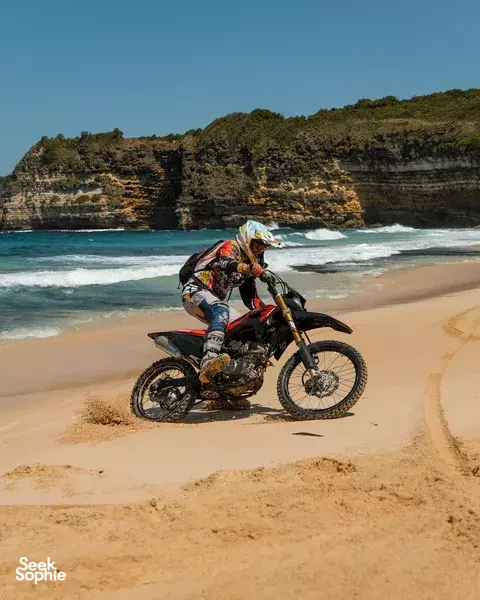 Single rider leans into sand on a dirt bike along a beach in Lombok during Mud n Gears’ Coastal Trail lesson