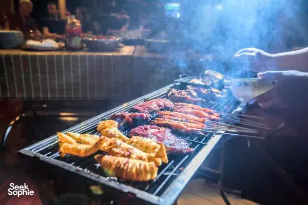 Charcoal barbecue on the deck of Cat Ba Ocean Cruises, with skewers grilling for a casual dinner during a 3D2N cruise