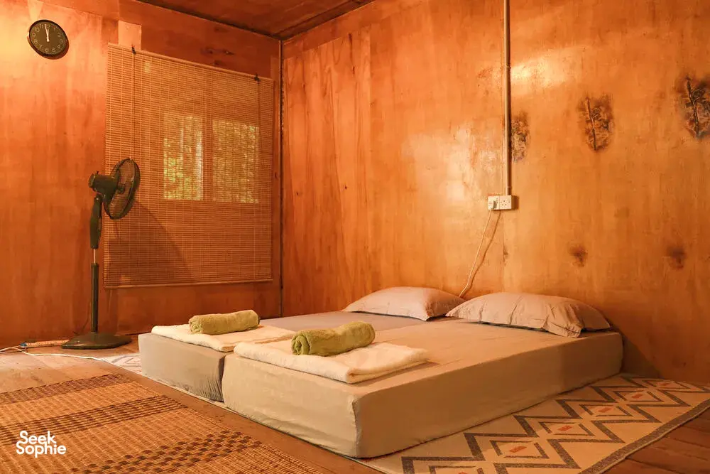 Cozy bedroom with a woven mat, pillows and wooden walls inside Ngapuh Homestead in Kuchingβs Bidayuh ancestral land