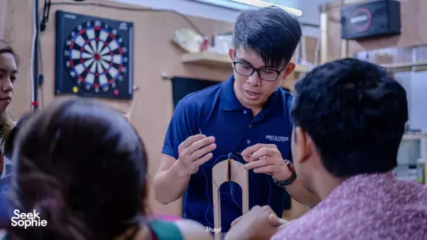 Leather instructor explaining clutch construction to a small group at a Singapore making studio — workshops in Singapore